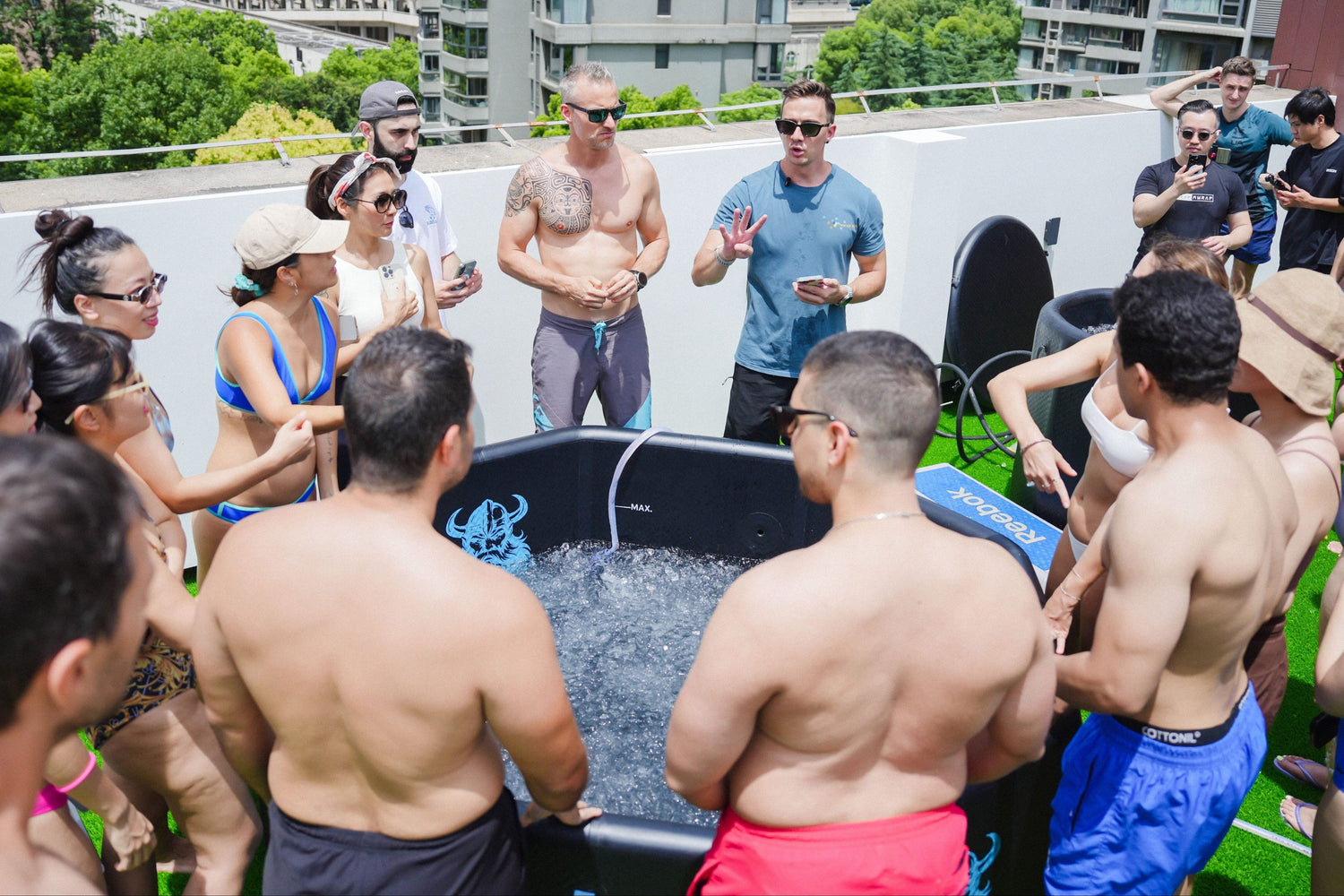 Group of people around a hot tub on a rooftop with cityscape in the background